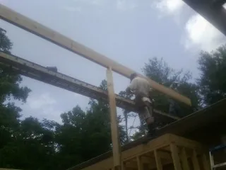 Carpenter setting a ridge beam over a new addition frame — Ice Dam Removal by Roofing Brothers in Falls City