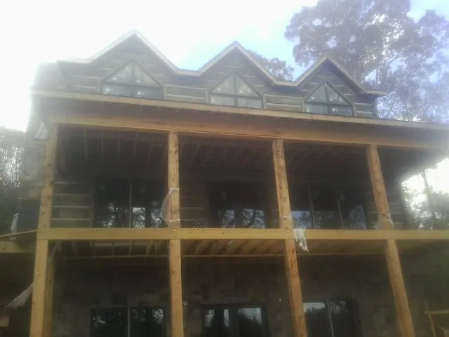 Dormers and porch framing on a large log home under construction — Roof Coating work by our crew in Falls City