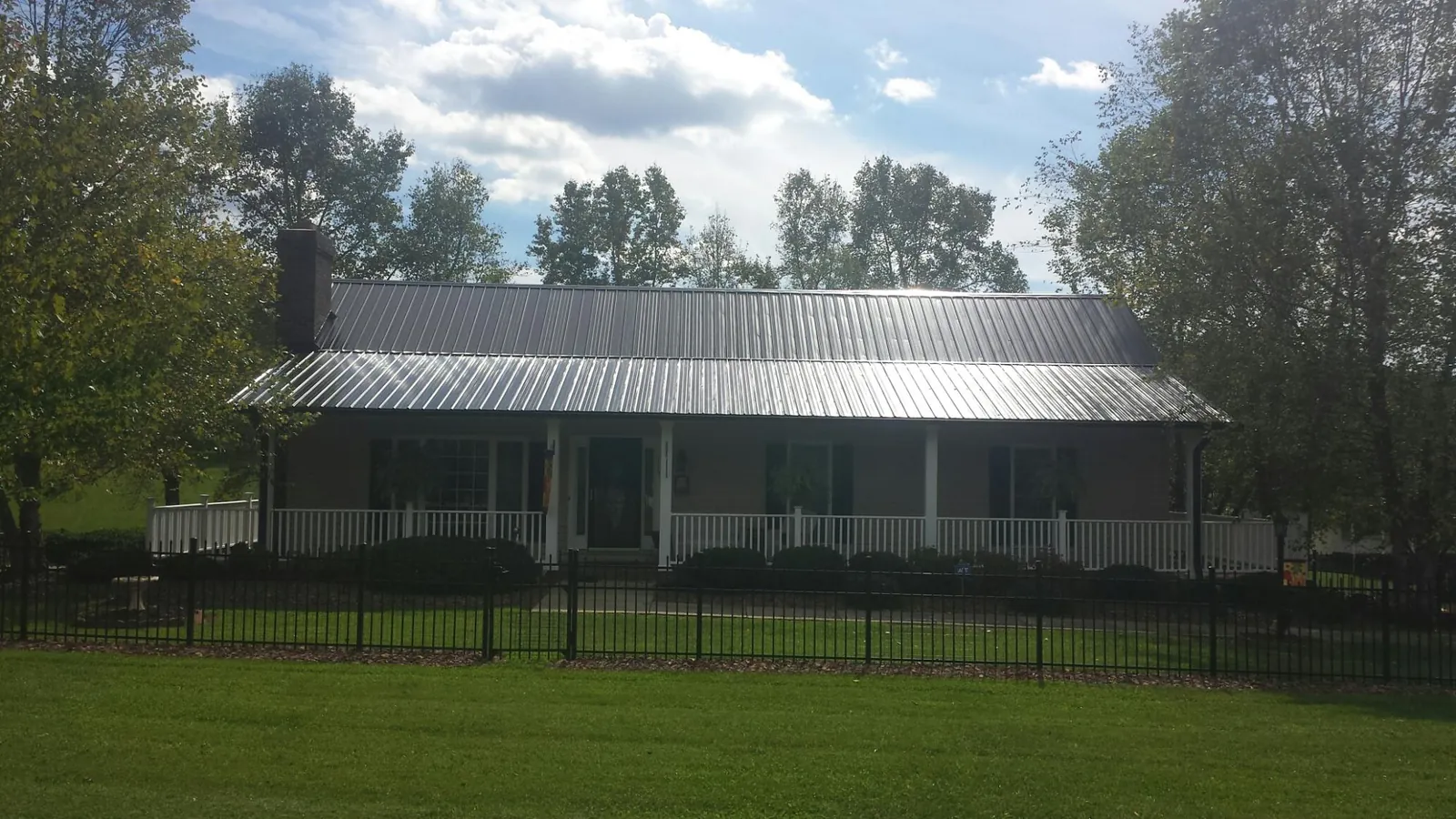 Gray metal roof on a brick ranch with a full width front porch — Gutter Guard Installation work by our crew in Falls City