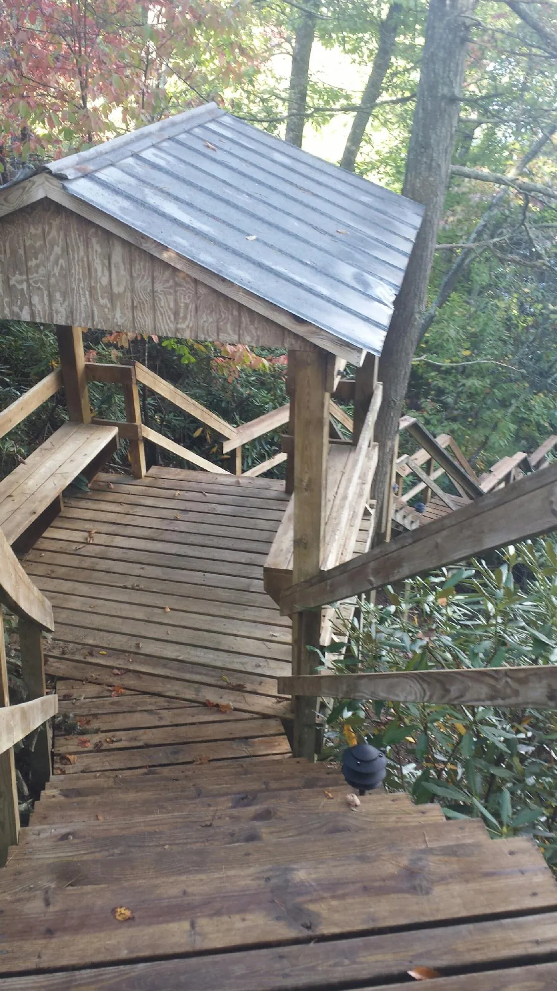 Metal roofed shelter over wooden steps on a wooded walkway — Skylight Repair & Installation work by our crew in Falls City