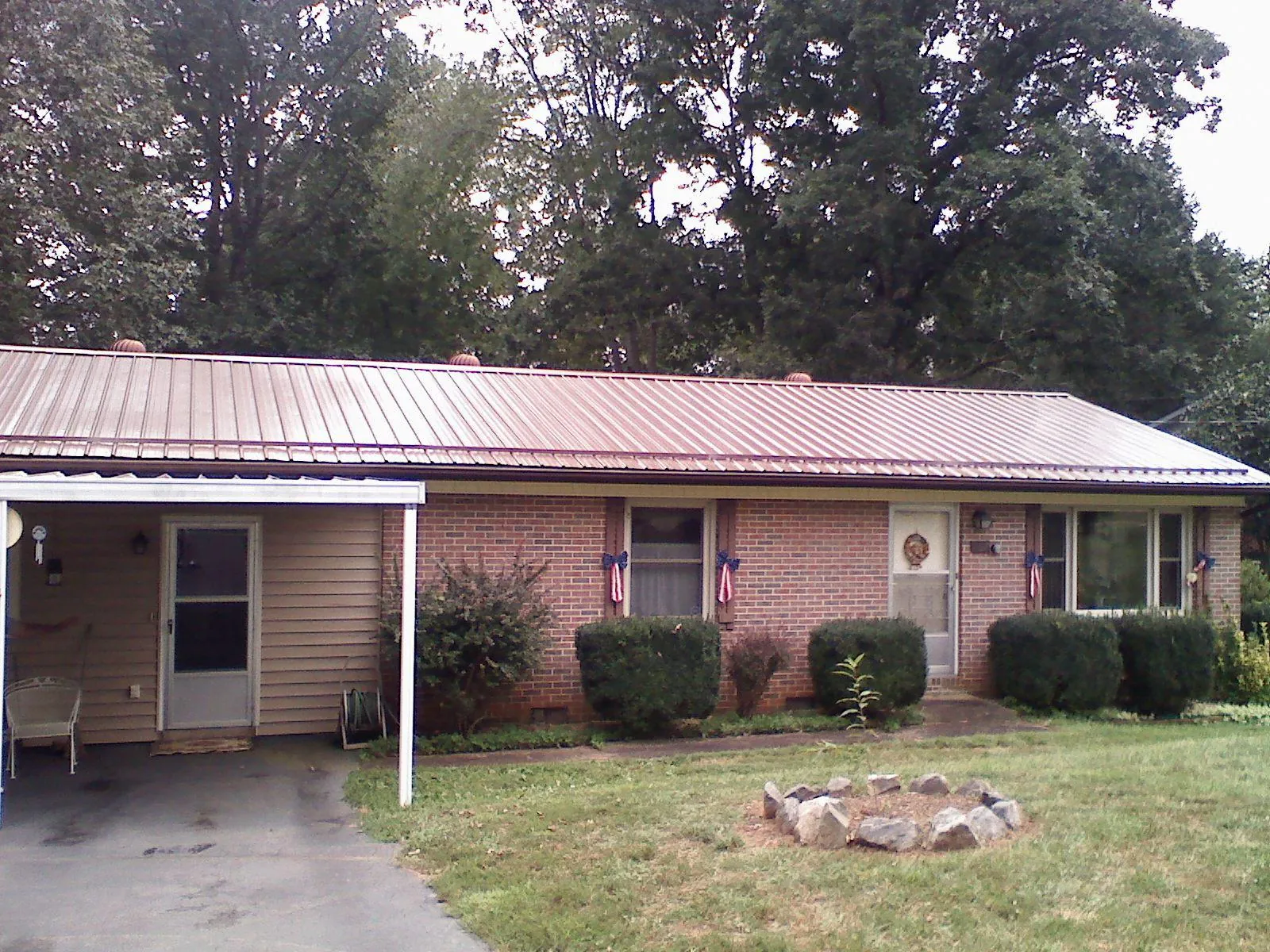 Bronze metal roof and carport on a brick ranch home — Roof Repair work by our crew in Falls City