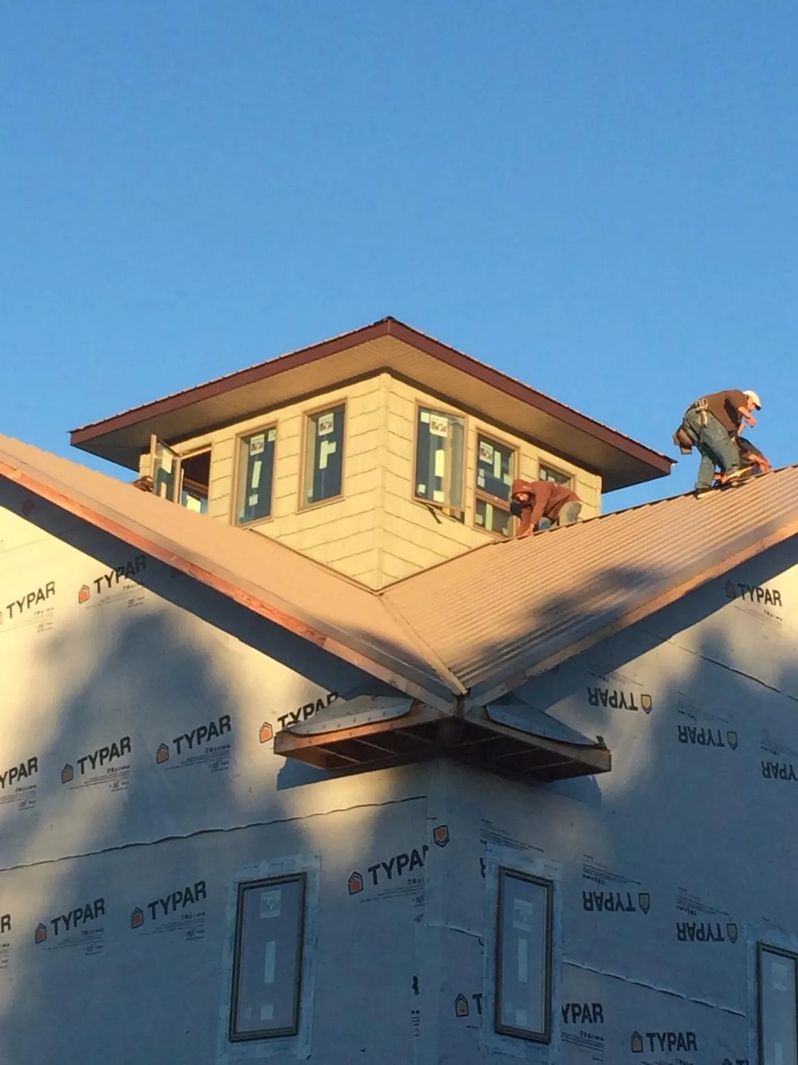 Roofers working around a rooftop cupola on a new metal roof at sunset — Roof Waterproofing in Falls City by Roofing Brothers